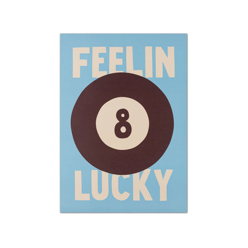 A square graphic print featuring a light blue background with the words 'FEELIN LUCKY' in cream lettering and a large dark brown and cream billiard 8-ball centered over the text.